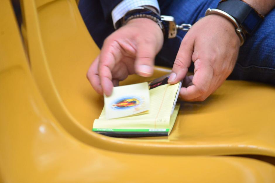 Un peque&ntilde;o libro de rezos tiene en sus manos Gustavo Alejos, acusado en el caso de Cooptaci&oacute;n del Estado. (Foto: Jes&uacute;s Alfonso/Soy502)
