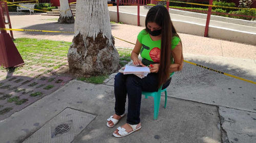 Joven toma clases en línea con su celular en una calle de México