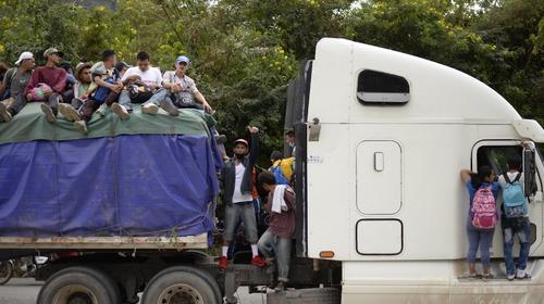 Migrantes arriesgan la vida al viajar colgando sobre un tráiler
